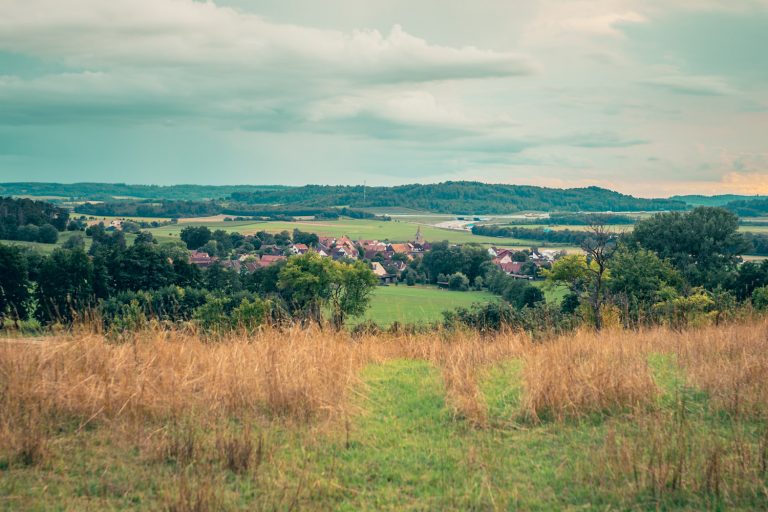 Blick über Breitenau in der sommerlichen Abenddämmerung. Es ziehen Regenwolken auf.